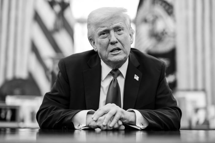 Donald Trump speaking with reporters while seated in the Oval Office.