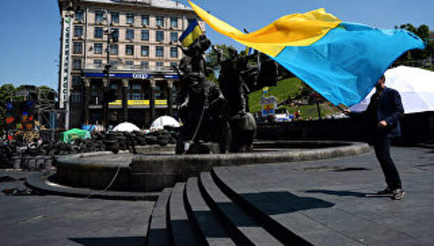 Молодой человек с украинским флагом у памятника основателям Киева на площади Независимости