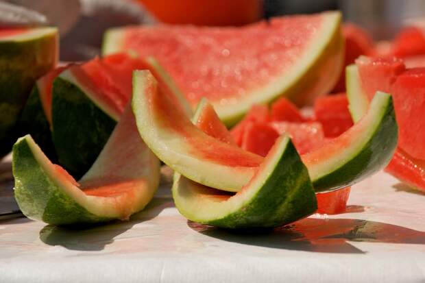 Selective focus image of sliced watermelon glistening in the sunlight during a picnic.