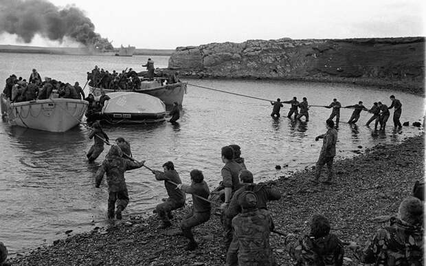 5 Survivors from HMS Sir Galahad (ablaze in the background) are hauled ashore by colleagues at Bluff Cove East Falkland after the ship was hit by an Argentinian air attack on June 29 1982 during the Falklands conflict.jpg