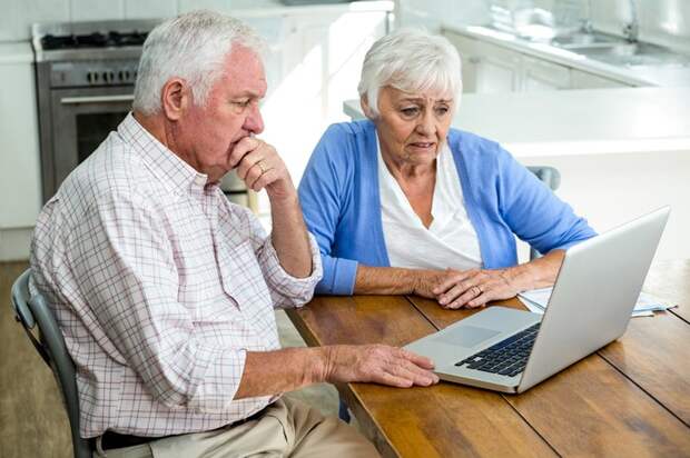 Older man and woman looking at laptop with worried expressions.