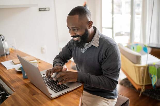 A smiling person at a laptop.