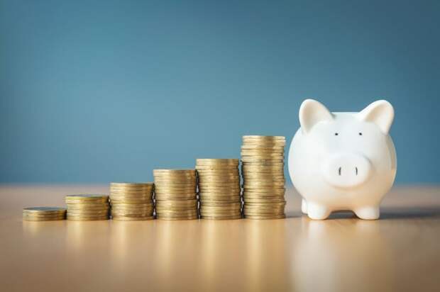 Coins in progressively larger stacks beside a piggy bank.