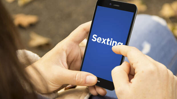 sexting concept: woman holding a digital generated smartphone with sexting on the screen. Graphics on screen are made up.