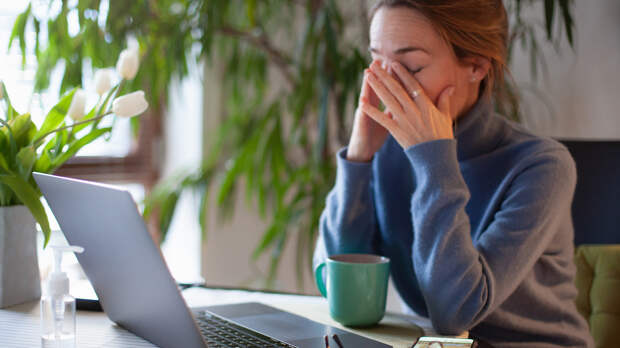 Woman rubbing her eyes in front of laptop. Working in home office during Covid-19 lockdown.