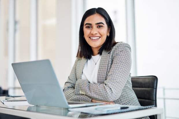 A smiling person at a laptop.