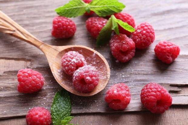 Ripe sweet raspberries in spoon on table close-up