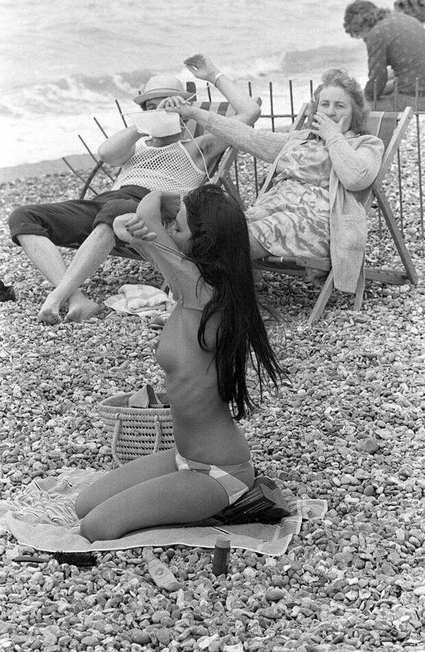 Женщина загораживает обзор мужу, чтобы тот не смотрел на раздевающуюся на пляже девицу. история, ретро, фото