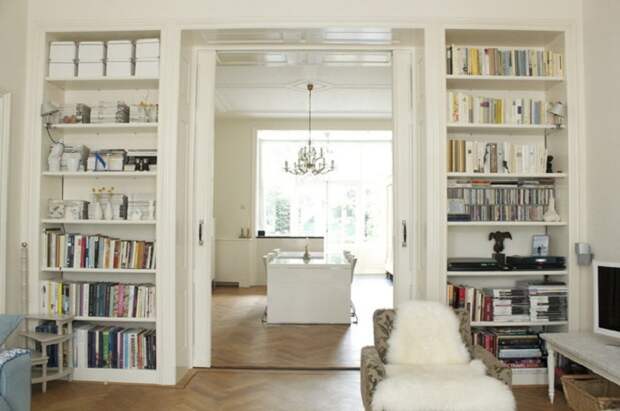 Прекрасная белоснежная комната с книжными стеллажами по обе стороны от дверной арки.