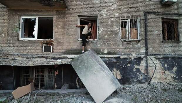 Мужчина выбирается через окно жилого дома в Донецке. Архивное фото