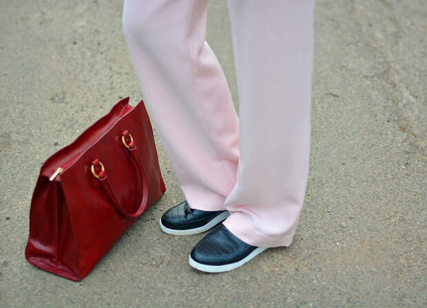 Pastel pink trousers, black slip on sneakers, cherry red tote