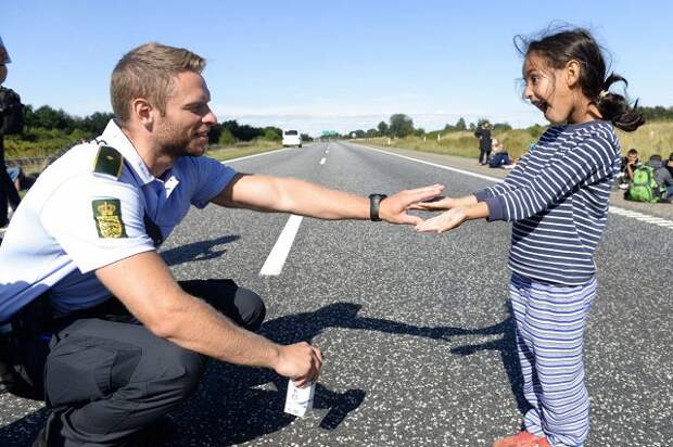 Датский полицейский играет с девочкой-мигрантом на датско-немецкой границе