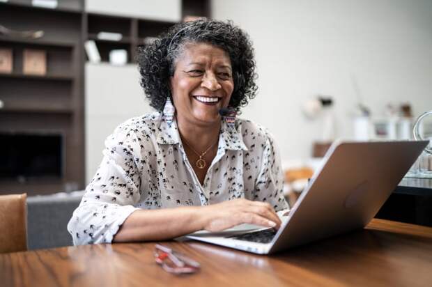 A smiling person at a laptop.