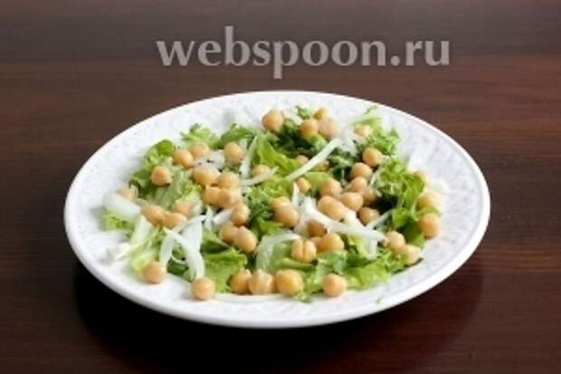 На тарелку выложить листья салата, немного разного лука и кинзы. Рассыпать часть гороха нут.
