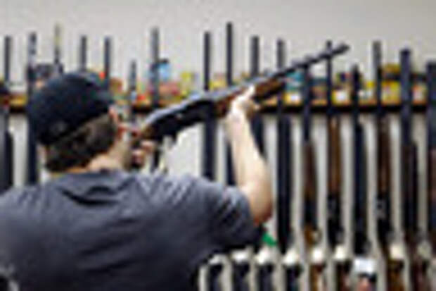 FILE - In this Wednesday, Dec. 19, 2012 file photo, a customer checks out a shotgun at Burdett & Son Outdoor Adventure Shop in College Station, Texas. The divide between those who favor gun control and those who don't has existed for decades, separating America into hostile camps of conservative vs. liberal, rural vs. urban. As the nation responds to the massacre of 20 children and six adults in Newtown, Conn., the gulf has rarely felt wider than now. (AP Photo/Pat Sullivan, File)