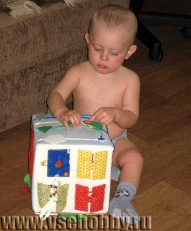 малыш играет с развивающим кубиком ручной работы