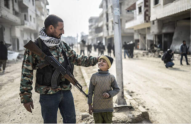Курдский боец со своим сыном на улице Кобани (Сирия) после восстановления контроля над городом, захваченным ИГИЛ интересно, люди, мир, подборка, фотографии