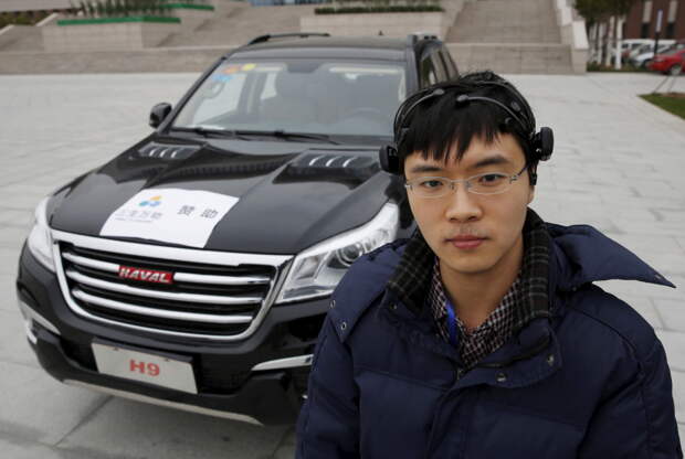 Researcher Zhang Zhao wearing a brain signal-reading equipment poses with a vehicle which can be controlled with his brain wave, during a demonstration at Nankai University in Tianjin, China, November 17, 2015. REUTERS/Kim Kyung