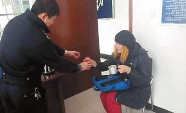Chinese policeman offers a hot drink to a Russian woman