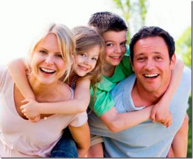 Couple giving two young children piggyback rides smiling