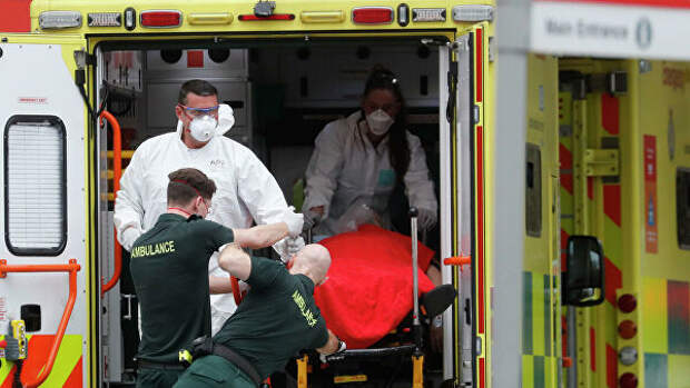 Медицинские сотрудники в защитных костюмах, доставляют пациента в больницу Святого Томаса в Лондоне, Британия