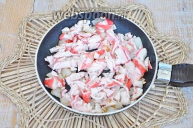 Выложить крабовое мясо и обжарить с луком.