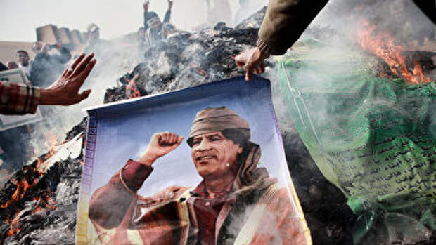 Жители Бенгази сжигают портреты Муамара Каддафи, плакаты с его цитатами и Зеленую книгу Каддафи. Архивное фото