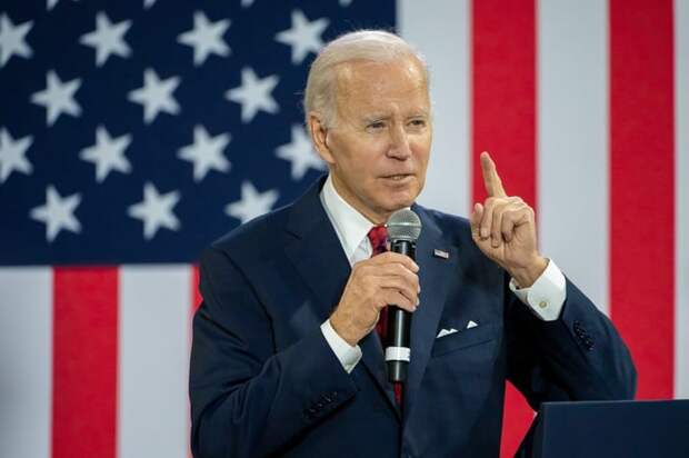 President Joe Biden delivering remarks from behind a podium, with a large American flag in the background.