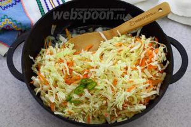 Добавьте капустную смесь, по вкусу острый перец. Перемешайте. Жарьте на среднем огне 15-20 минут. Периодически мешайте деревянной лопаткой.
