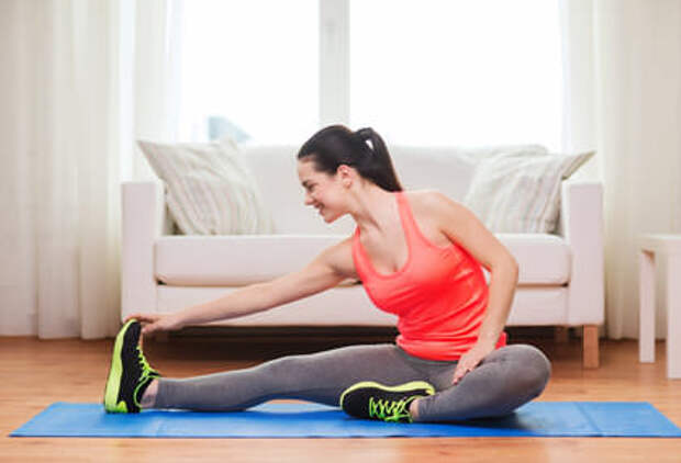 smiling teenage girl streching on floor at home