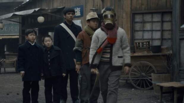 Moz, Noa and friend with gas mask walk in a group