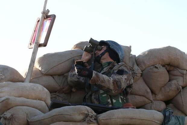 A member of the Kurdish Peshmerga forces looks through binoculars during clashes with Islamic State militants in the town of Sinjar