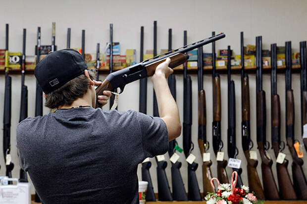 FILE - In this Wednesday, Dec. 19, 2012 file photo, a customer checks out a shotgun at Burdett & Son Outdoor Adventure Shop in College Station, Texas. The divide between those who favor gun control and those who don't has existed for decades, separating America into hostile camps of conservative vs. liberal, rural vs. urban. As the nation responds to the massacre of 20 children and six adults in Newtown, Conn., the gulf has rarely felt wider than now. (AP Photo/Pat Sullivan, File)