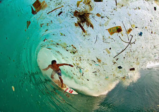 Сёрфер покоряет волну, полную мусора, у острова Ява — самого густонаселённого в мире.