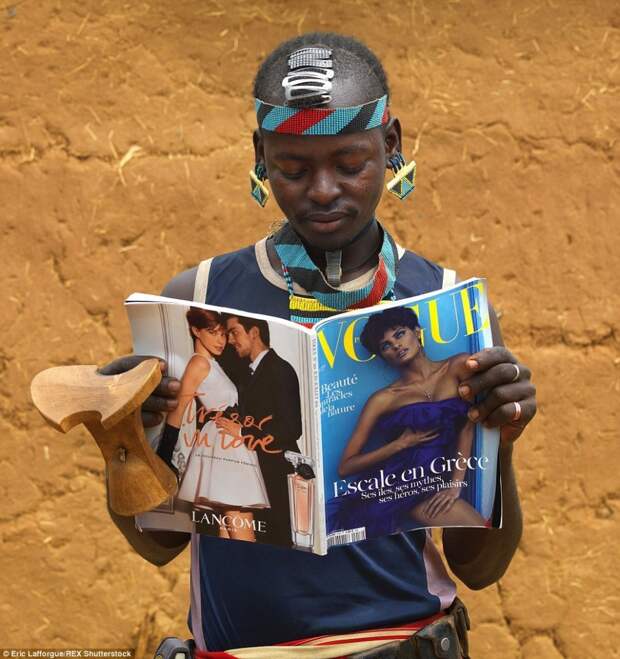 Традиционная культура африканских аборигенов и продукт западного мира на одном снимке: мужчина народа дасанеч смотрит картинки в глянцевом журнале Vogue. 