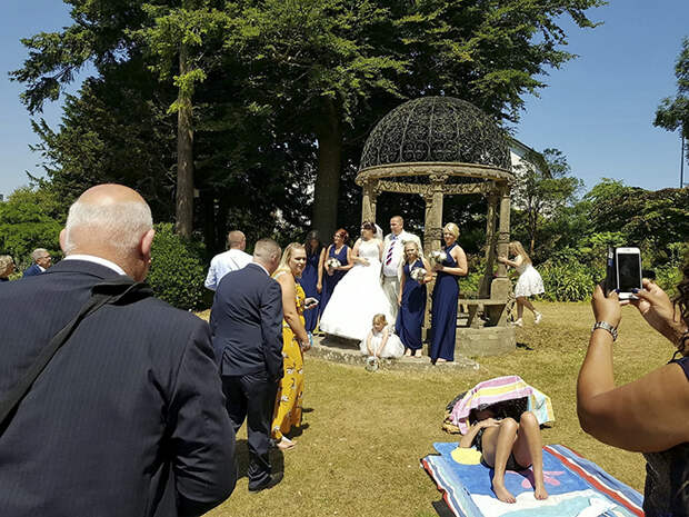 A wedding couple were left disgruntled when a shameless sunbather photobombed their wedding pictures by refusing to move. See story SWWEDDING. Newly-weds Mark Ling,49, and Mandy Cripwell, 35, were married in church on Saturday, and retired to a renowned beauty spot and public park to take what they hoped would be the perfect snaps. But their idyllic sun-kissed scene soon turned was ruined by a stubborn sunbather who had taken up residence on the green. The family of Torquay, Devon, say they asked the scantily-clad woman to move but she refused, and the wedding party were forced to pose for pictures around her. Mark's son, 24-year-old Marcus Ling, even approached the woman and asked her to move - but she pretended to be asleep.