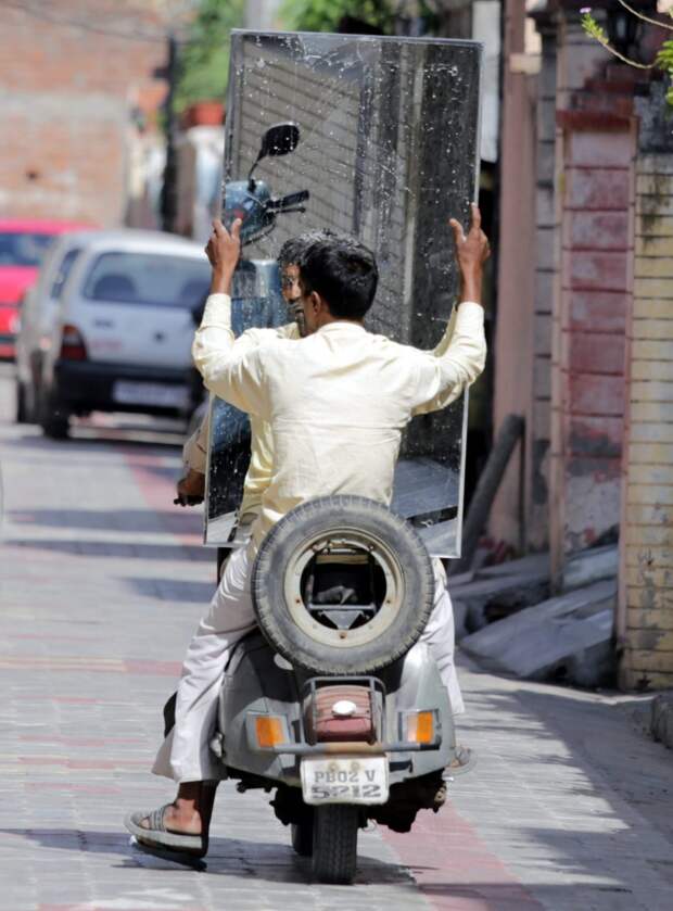 An Indian man sits holding a mirror on the rear seat of a scooter in a street in Amritsar, India, 21 October 2015. (Photo by Raminder Pal Singh/EPA)