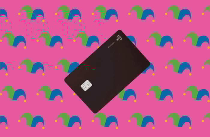 A black credit card against a pink background