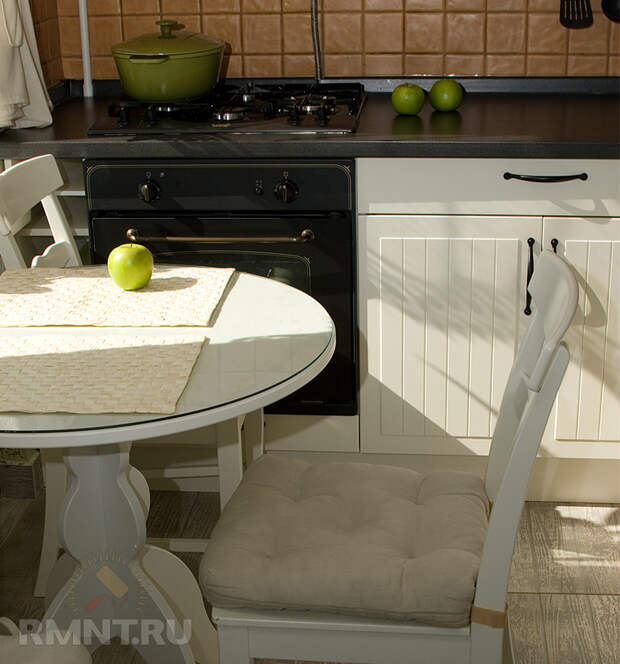 Кухня в скандинавском стиле. Белый круглый столик, мягкие стулья, ламинат, который отлично имитирует доску светлого оттенка, бежевый кухонный фартук