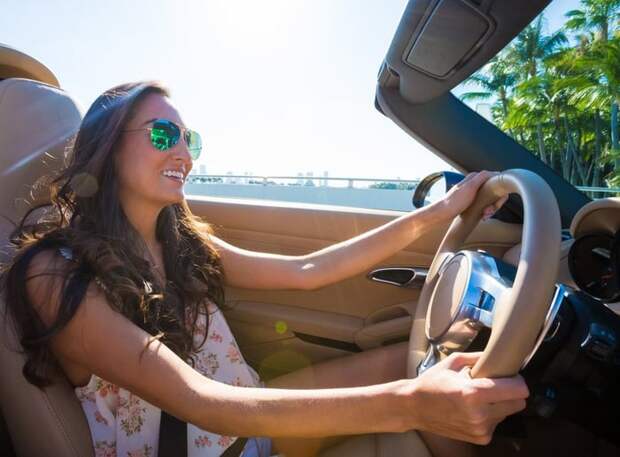 Young woman driving convertible near the coast.