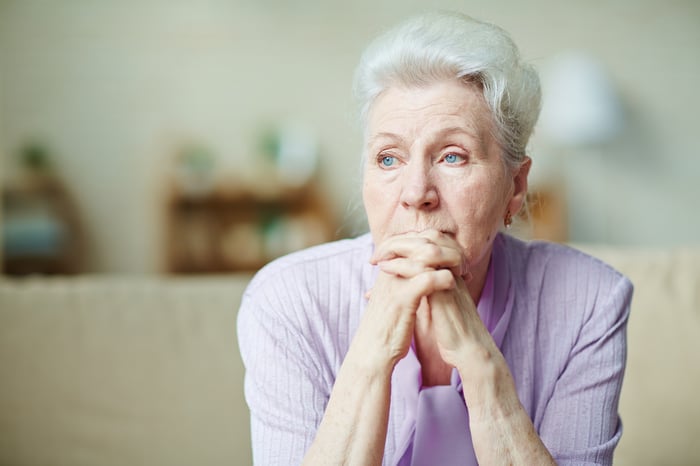 A person clasps their hands, looking worried.