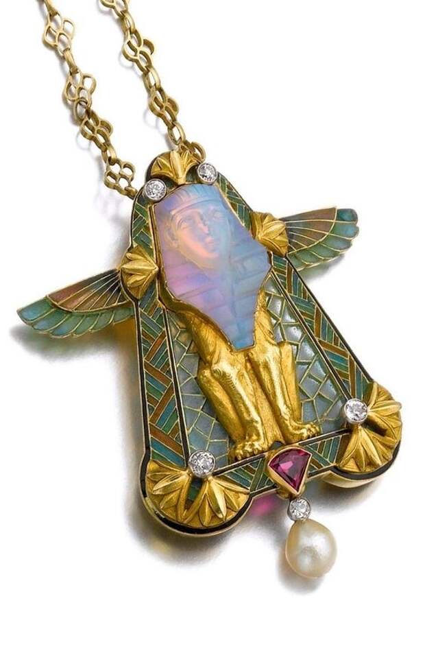 Philippe Wolfers - An Art Nouveau gem set, enamel and diamond pendant. The chain composed of a line of quatrefoil gold motifs, supporting a detachable pendant designed as a sphinx set with a carved opal, the mount embellished with plique-à-jour enamel, a triangular ruby, brilliant-cut diamonds and a drop-shaped cultured pearl, maker's mark for Philippe Wolfers.