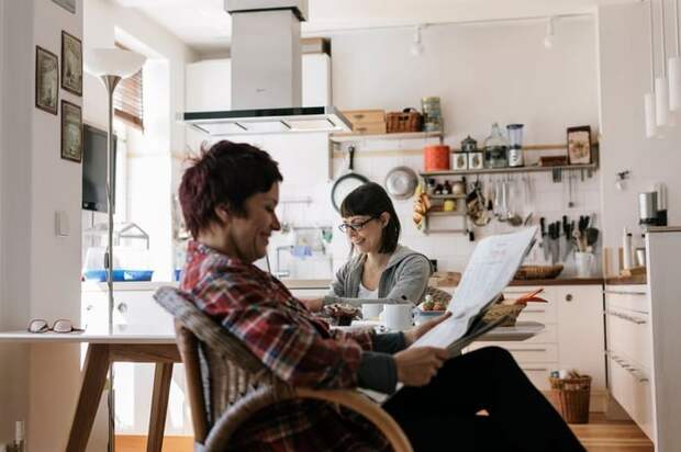 Two people in a kitchen reading the news.