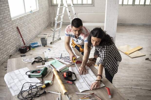 A couple in an empty loft apartment planning out home improvements.