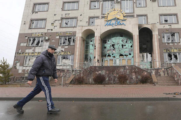 Мужчина проходит мимо разгромленного офиса правящей казахстанской партии Нур Отан в городе Алматы.