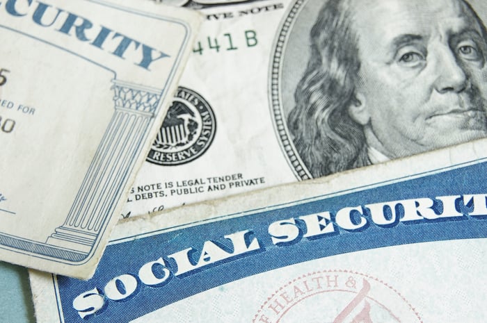 A Social Security card laying atop a $100 bill.