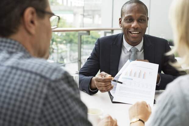 Couple talking with financial advisor and looking at paperwork.