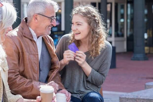 Parents giving credit card to excited teen daughter.