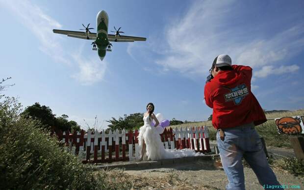 Невеста в свадебном наряде позирует на фоне пролетающего пассажирского самолёта в аэропорту Тайбэй Соншан, Тайвань.
