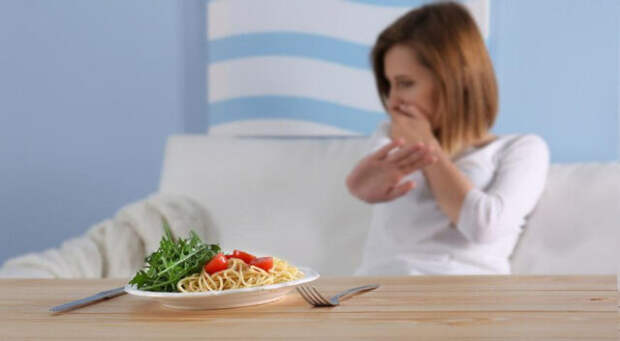 женщина отказывается от тарелки со спагетти